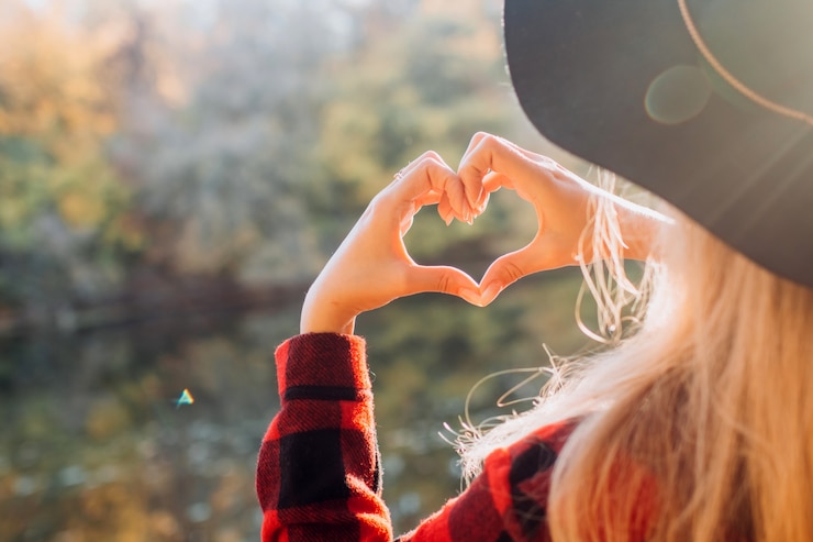Fotografie woman in black hat doing heart with her hands outdoors