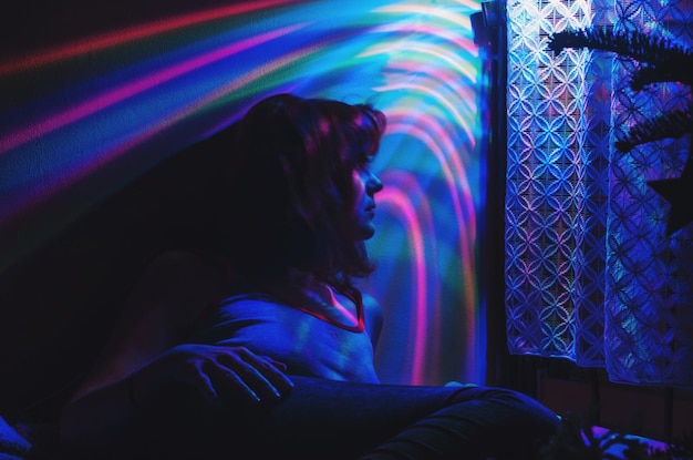 woman relaxing by colorful lights at home