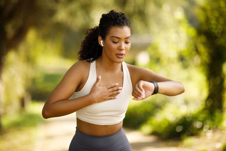 Fotografie woman runner checking smartwatch pausing and breathing in run outdoors