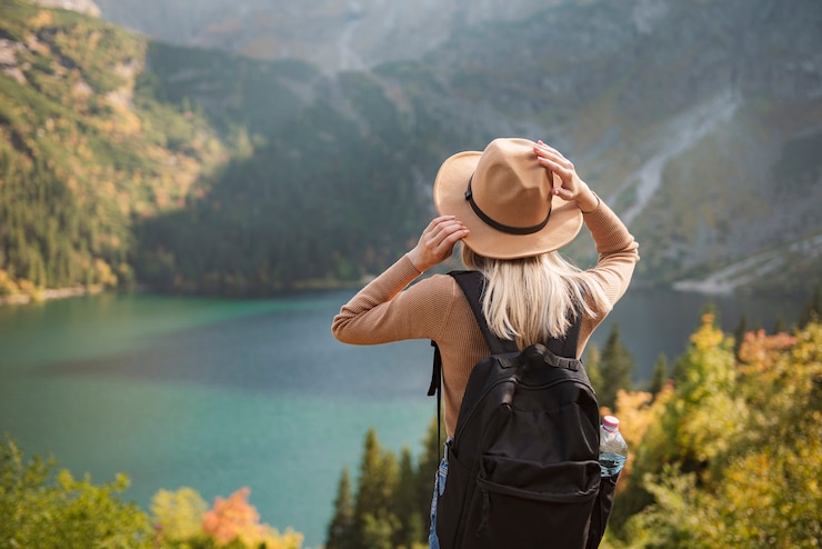 Fotografie woman traveler wearing hat and looking at amazing mountains and lake, wanderlust travel concept. lake morskoy eye in the polish tatras.