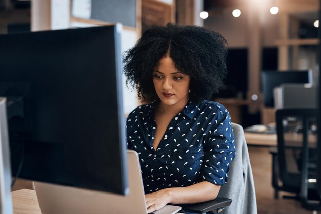 Woman typing and serious for working in office keyboard and laptop for journalist research and writing Workplace employee and person with computer planning and project for headline of article