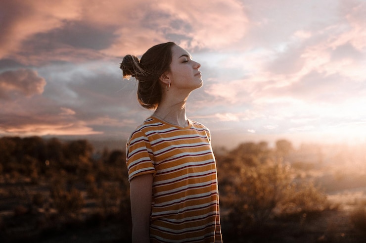 Fotografie woman with eyes closed standing against sky during sunset