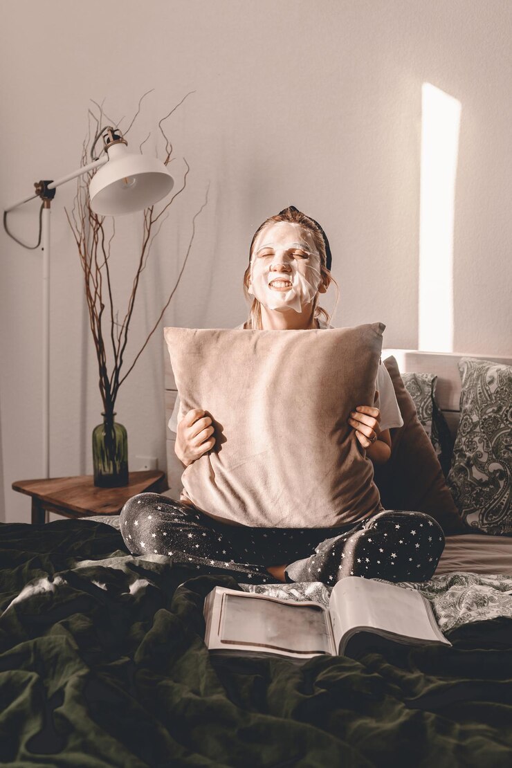 Fotografie woman with face mask holding cushion while sitting on bed at home