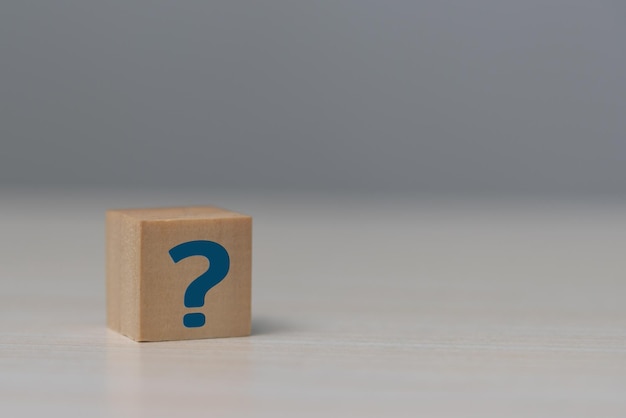 wooden cube block shape with sign question mark symbol on table