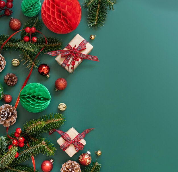 Wrapped gift boxes between Christmas decorations and green fir branches on green copy space