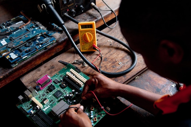 young adult repairing a computer motherboard in a workshop