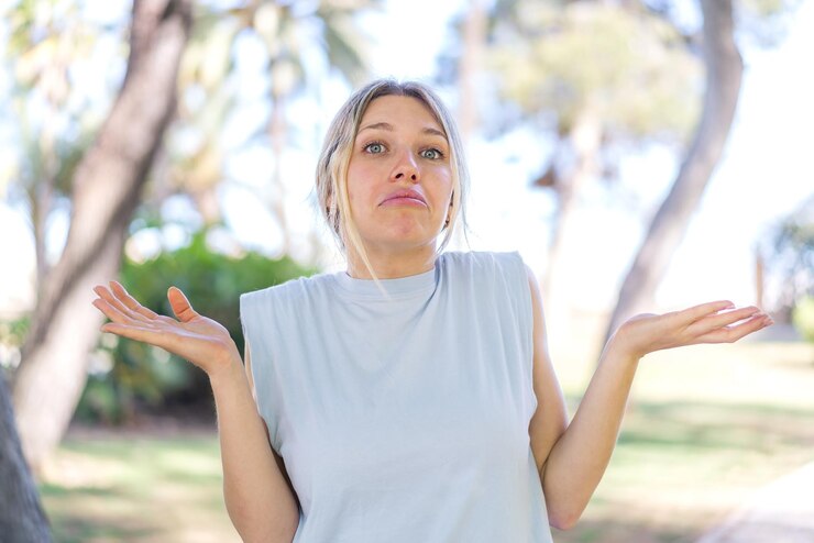 Fotografie young blonde woman at outdoors making doubts gesture