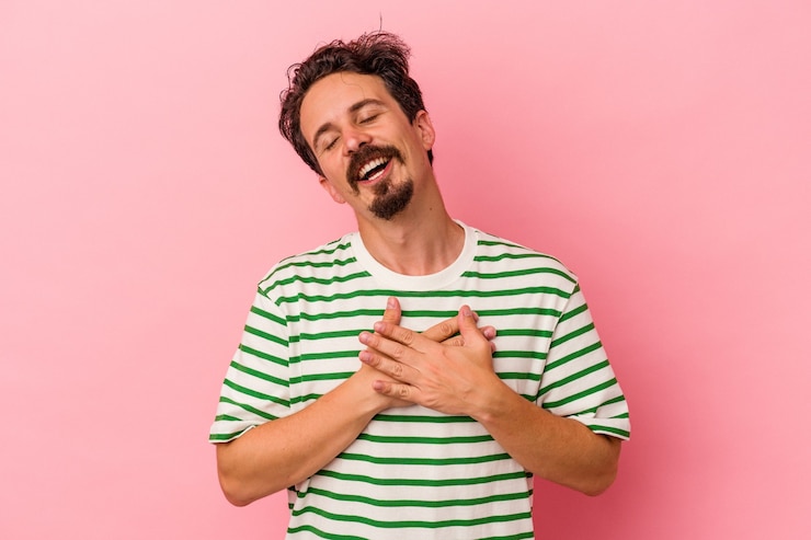 Fotografie young caucasian man isolated on pink background has friendly expression, pressing palm to chest. love concept.