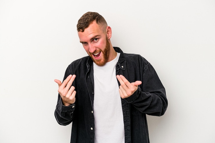 Fotografie young caucasian man isolated on white background pointing with finger at you as if inviting come closer.