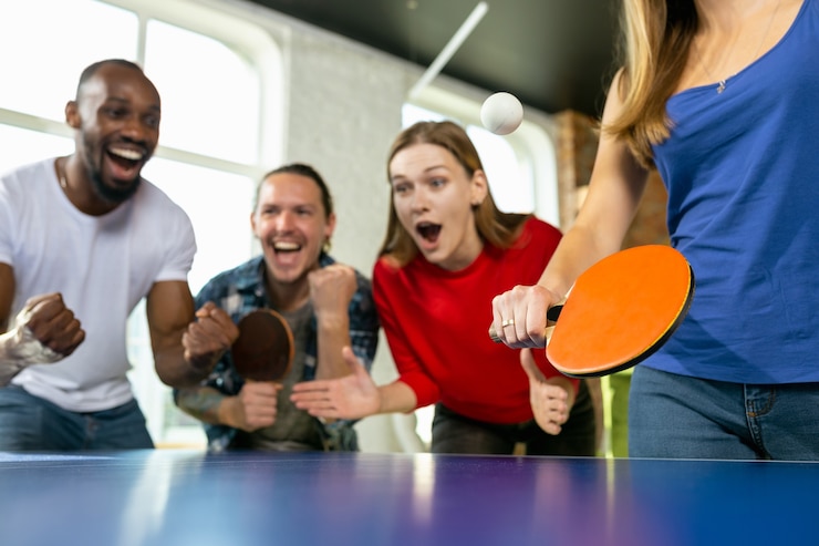 Fotografie young people playing table tennis in workplace, having fun