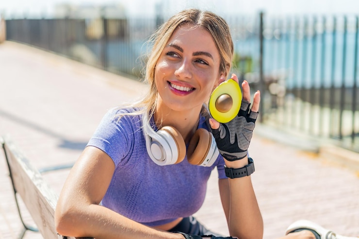 Fotografie young pretty sport woman at outdoors holding an avocado with happy expression