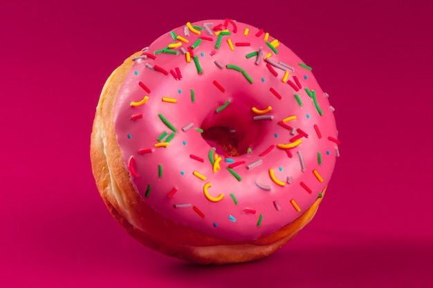 yummy glazed round donut on a bright pink background