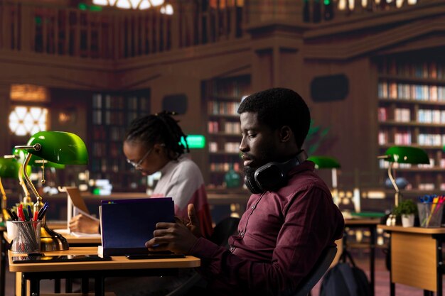 African american student opening textbook to complete handwritten class notes
