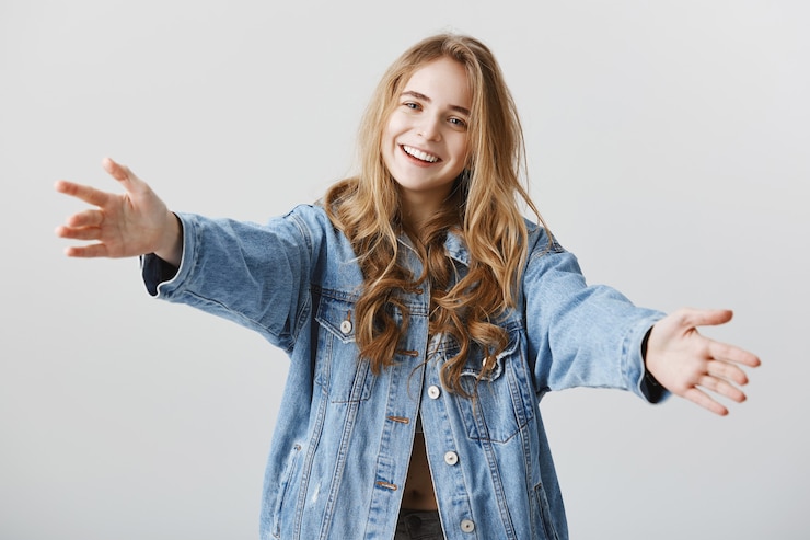 Zdarma Fotografie attractive blond girl smiling happy and spread hands sideways for hug, embracing or taking something