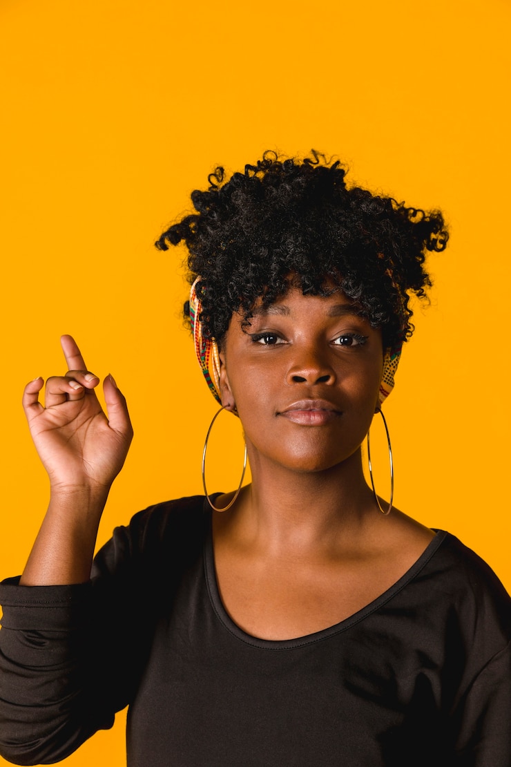 Zdarma Fotografie confident black curly young woman pointing up in studio