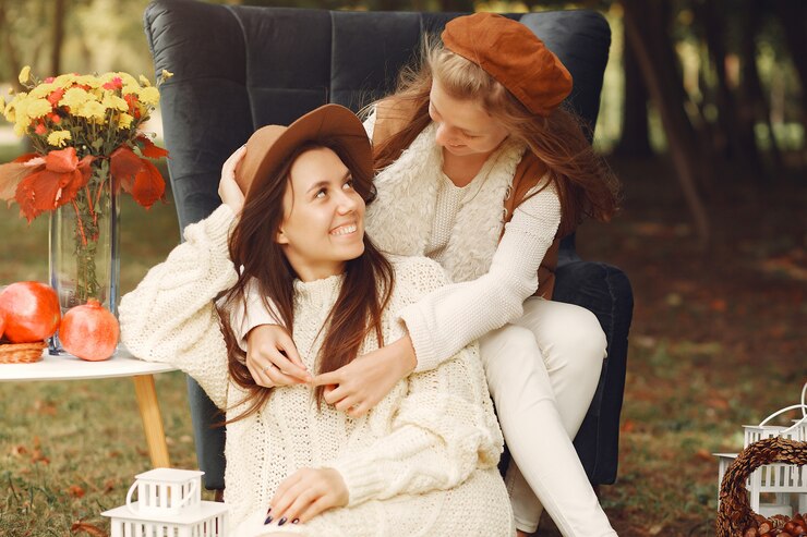 Zdarma Fotografie elegant and stylish girls sitting on a chair in a park