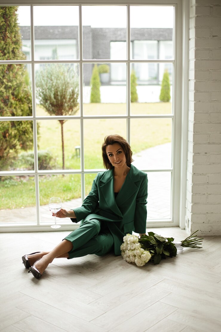 Zdarma Fotografie elegant caucasian woman with dark hair in green suit poses for the camera near the big bouquiet of white flowers and smiles