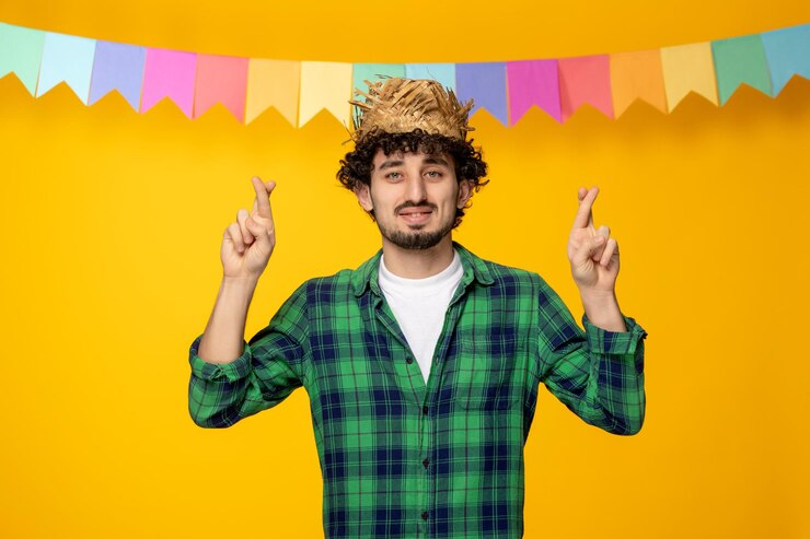 Zdarma Fotografie festa junina young cute guy in straw hat and colorful flags brazilian festival fingers crossed