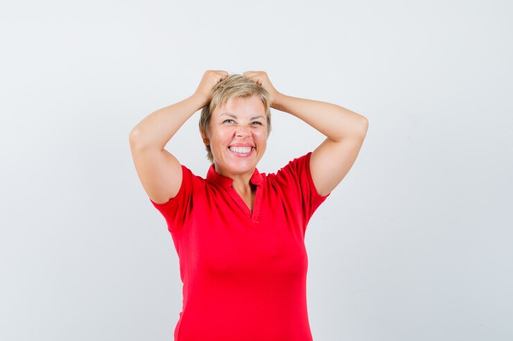 Zdarma Fotografie mature woman holding hands on head in red t-shirt and looking forgetful.