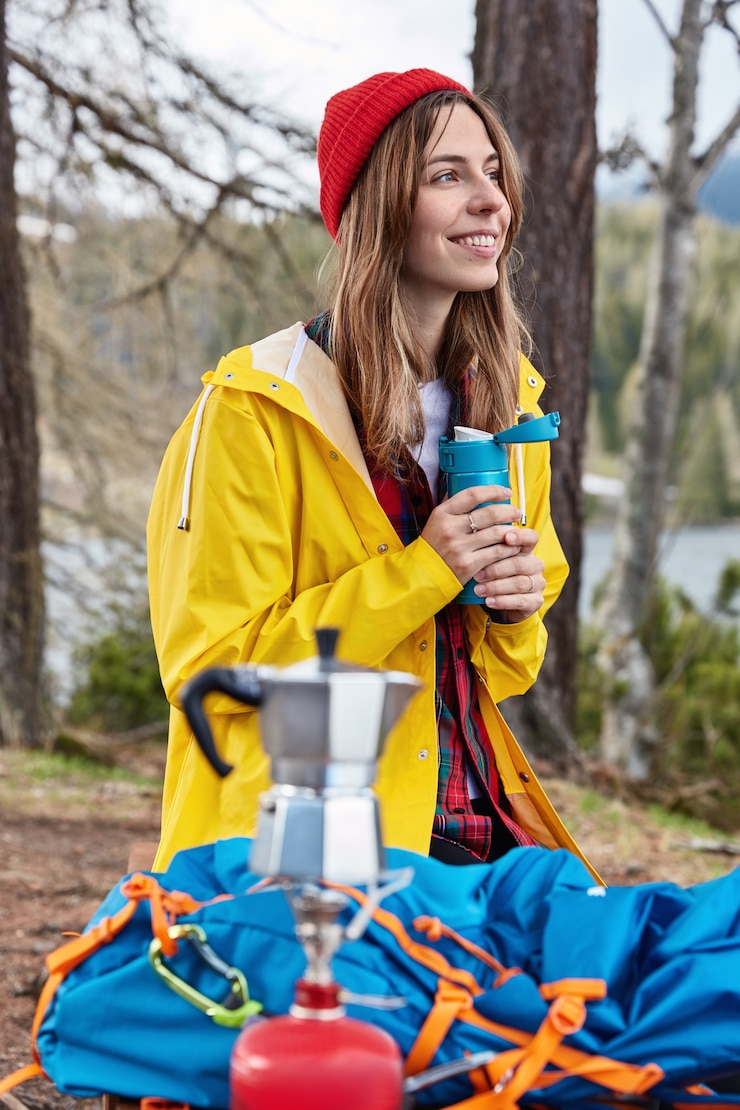 Zdarma Fotografie people and camping concept. satisfied female traveler drinks hot beverage from thermos after hiking