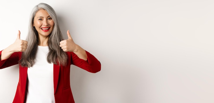 Zdarma Fotografie portrait of senior asian woman showing thumbup in approval wearing red blazer for office work recomm