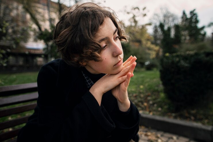 Zdarma Fotografie serious non binary person sitting on a bench thoughtfully