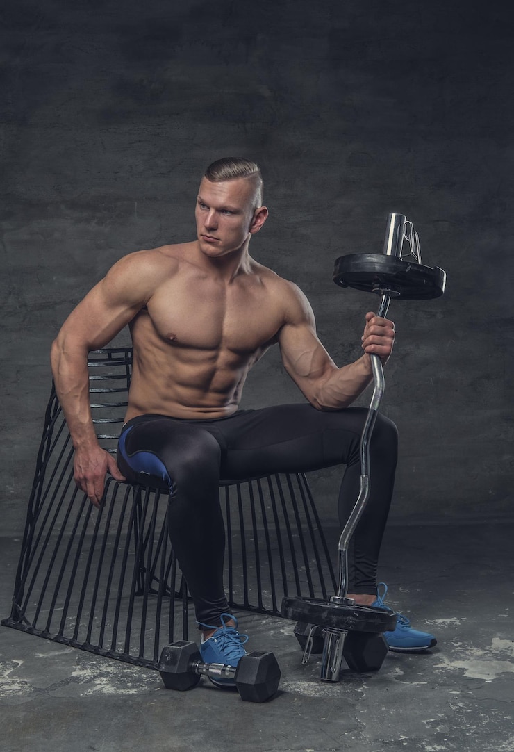 Zdarma Fotografie shirtless muscular man with barbell sits on a black chair.