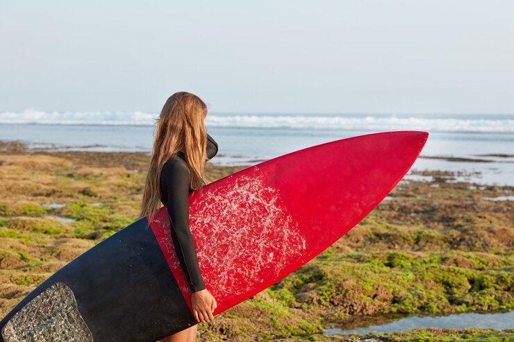 Zdarma Fotografie shot of active sporty woman carries red surfboard with waxed surface
