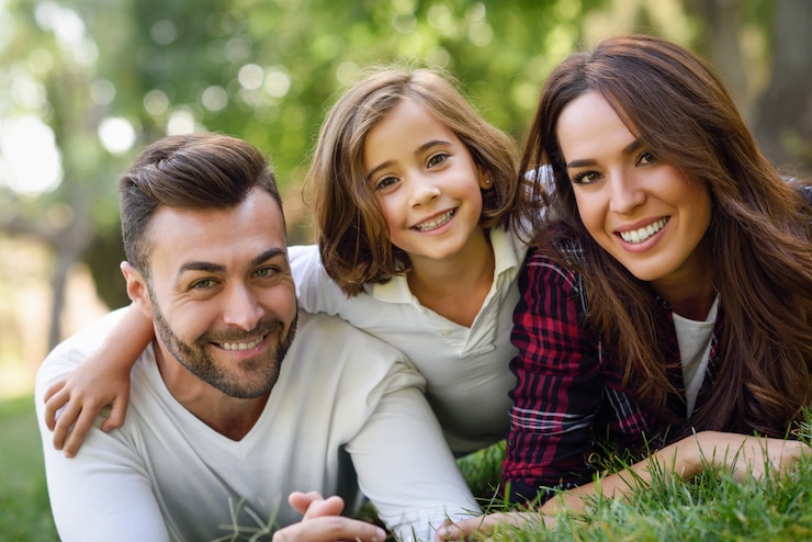 Zdarma Fotografie smiling couple lying on the lawn with their daughter