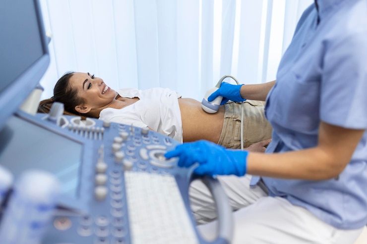 Zdarma Fotografie ultrasound diagnostic of stomach on abdominal to woman in clinic closeup view doctor runs ultrasound sensor over patient's girl tummy and looks at image on screen diagnosis of internal organs