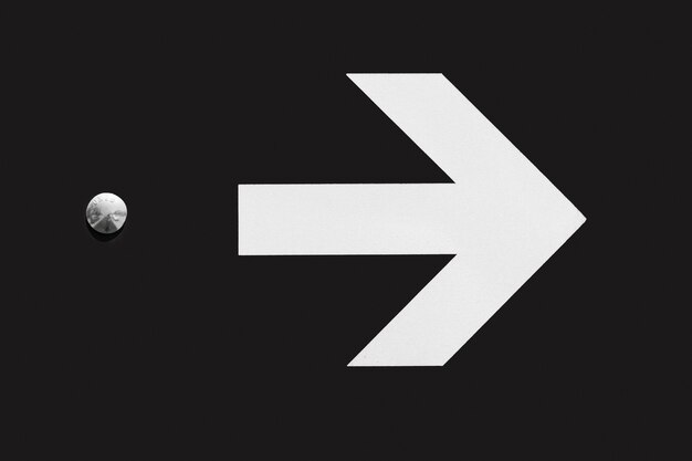 White arrow on black background with thumbtack