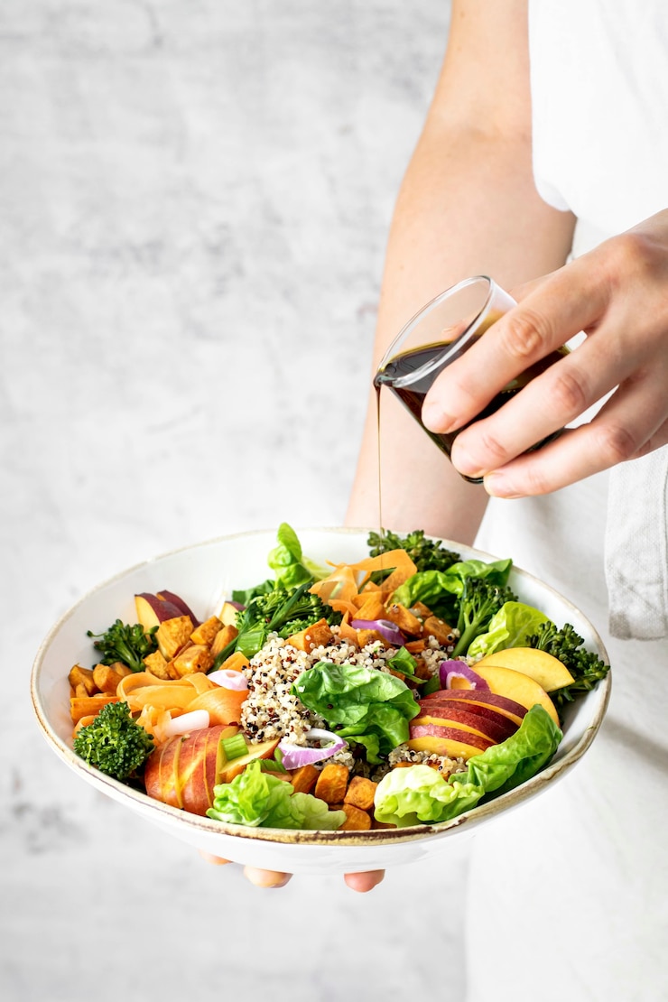 Zdarma Fotografie woman pouring pumpkin seed oil over sweet potato buddha bowl