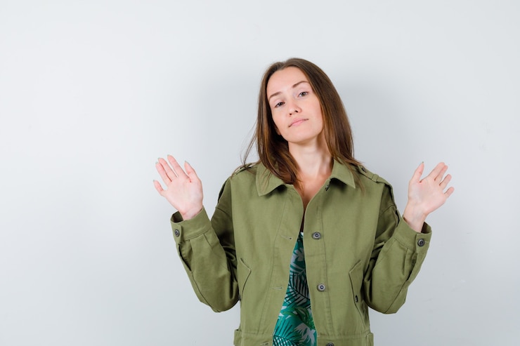Zdarma Fotografie young lady in blouse, jacket showing palms in surrender gesture and looking confident , front view.