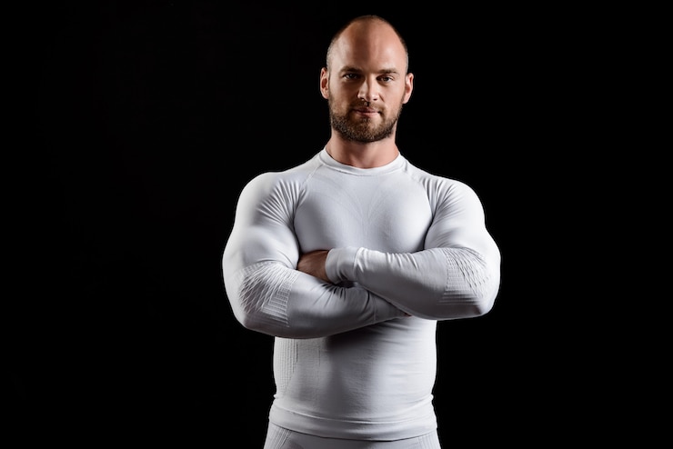 Zdarma Fotografie young powerful sportsman in white clothing over black wall.