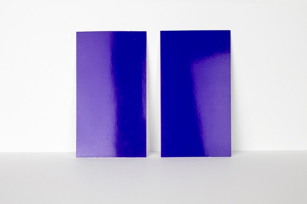 2 cartões de visita azuis em branco trancados na parede branca, tamanho de 3,5 x 2 polegadas