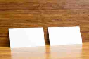 Foto grátis 2 cartões de visita em branco trancados na mesa de madeira texturizada