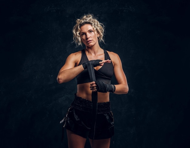A boxeadora experiente está posando para o fotógrafo enquanto usa bandagens protetoras.
