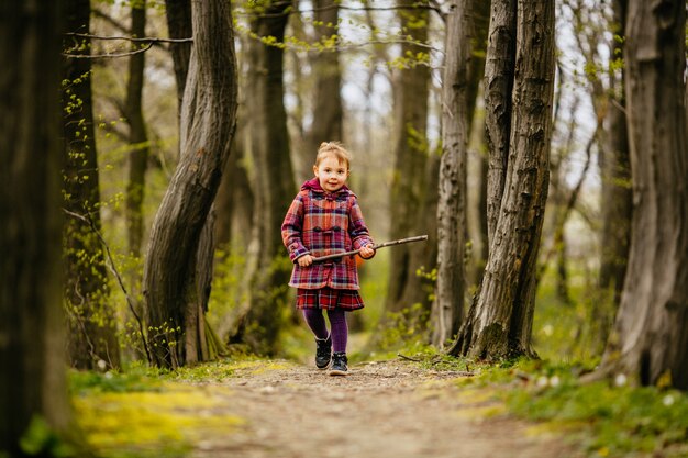 A criança pequena mantendo um baú e caminhando pelo parque