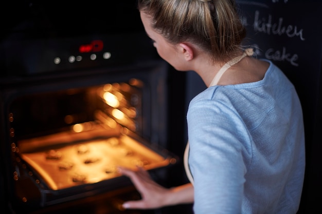 A dona de casa perfeita assando seus biscoitos favoritos