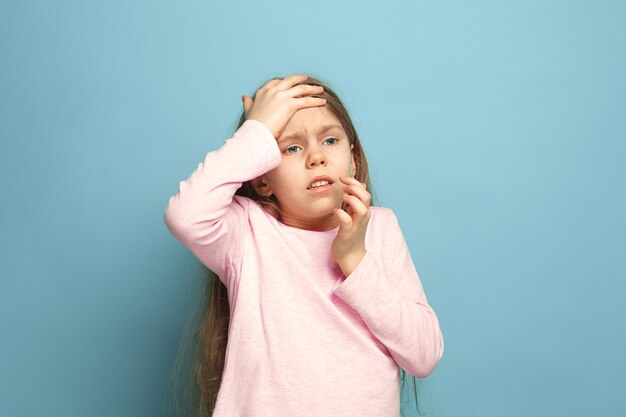 A dor de cabeça. Menina adolescente em um azul. Expressões faciais e conceito de emoções de pessoas