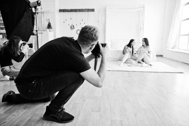 A equipe de dois fotógrafos atirando em garotas gêmeas de estúdio Fotógrafo profissional no trabalho