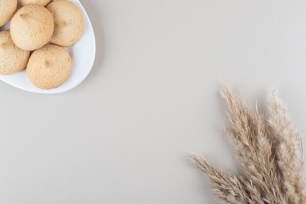 A erva-agulha caule ao lado de uma travessa de biscoitos no fundo de mármore.