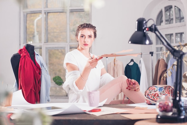 A estilista feminina trabalhando em um estúdio, sentada na mesa