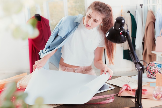 A estilista feminina trabalhando sentada na mesa