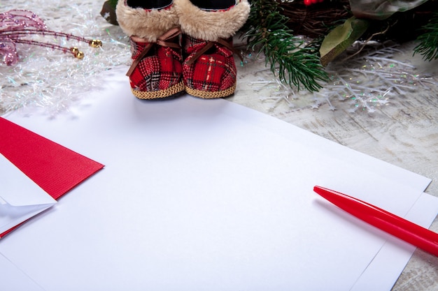 A folha de papel em branco na mesa de madeira com uma caneta e enfeites de natal.