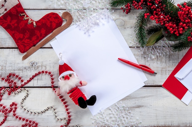 A folha de papel em branco na mesa de madeira com uma caneta e enfeites de natal.