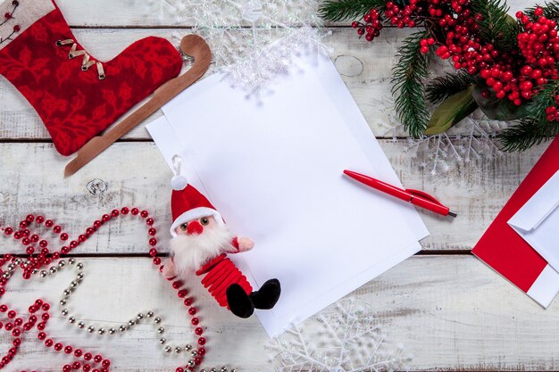 A folha de papel em branco na mesa de madeira com uma caneta e enfeites de Natal.