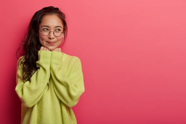 A foto horizontal de uma mulher de aparência agradável tem uma expressão sonhadora, parece com uma expressão alegre pensativa, imagina uma situação agradável, tem bochechas ruge