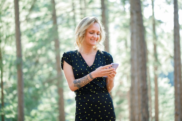 A garota blogueira sorridente está conversando no celular sobre o fundo da natureza