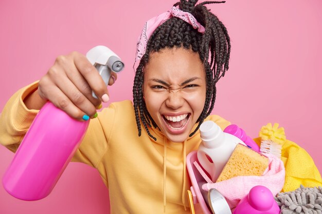 A governanta irritada limpa tudo com detergente para a roupa segura uma cesta cheia de produtos de limpeza